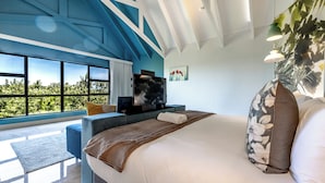 A modern bedroom with a large bed, a flat-screen TV, and a view of greenery through large windows. - Ultra-Luxury 4-Bedroom en-suite self catering Villa in Zimbali Coastal Resort (Ballito)