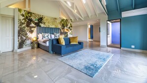 A spacious living room with a blue sofa, a large wall mural, and a polished floor. - Ultra-Luxury 4-Bedroom en-suite self catering Villa in Zimbali Coastal Resort (Ballito)