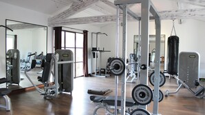 Ein Fitnessraum mit unterschiedlichen Trainingsgeräten, einer Bank und einem Boxsack.