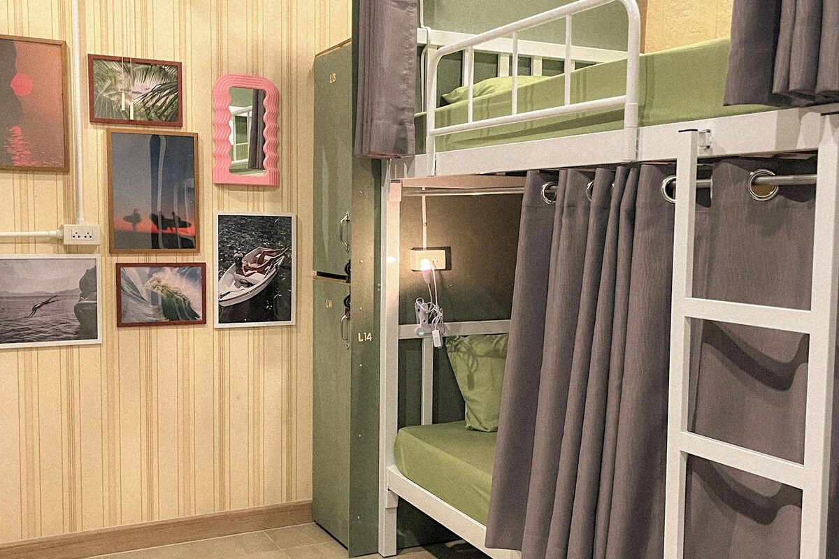 A bunk bed room with a green mattress, a wall-mounted light, and several framed pictures.