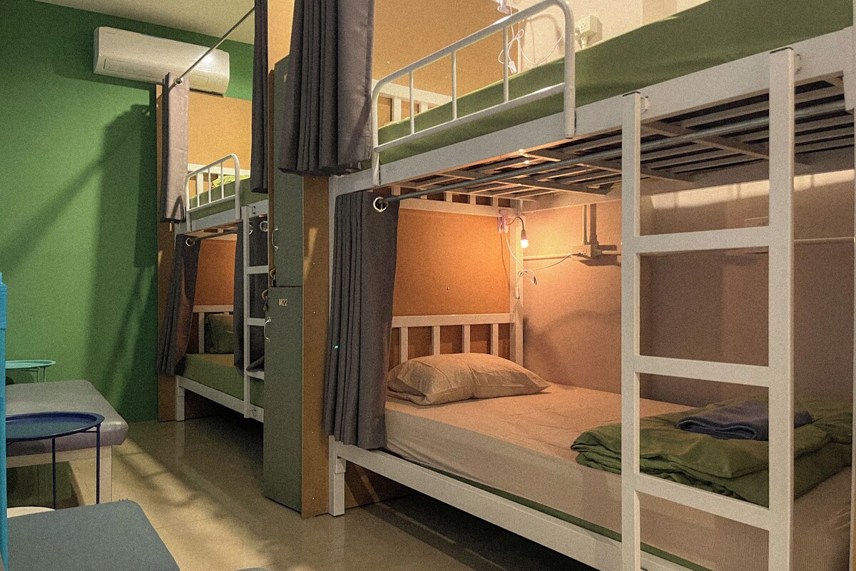 A bunk bed room with a desk and chair, a hanging light fixture, and a green wall.