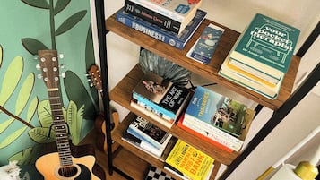 A bookshelf with various books, a guitar, and a checkered board game.