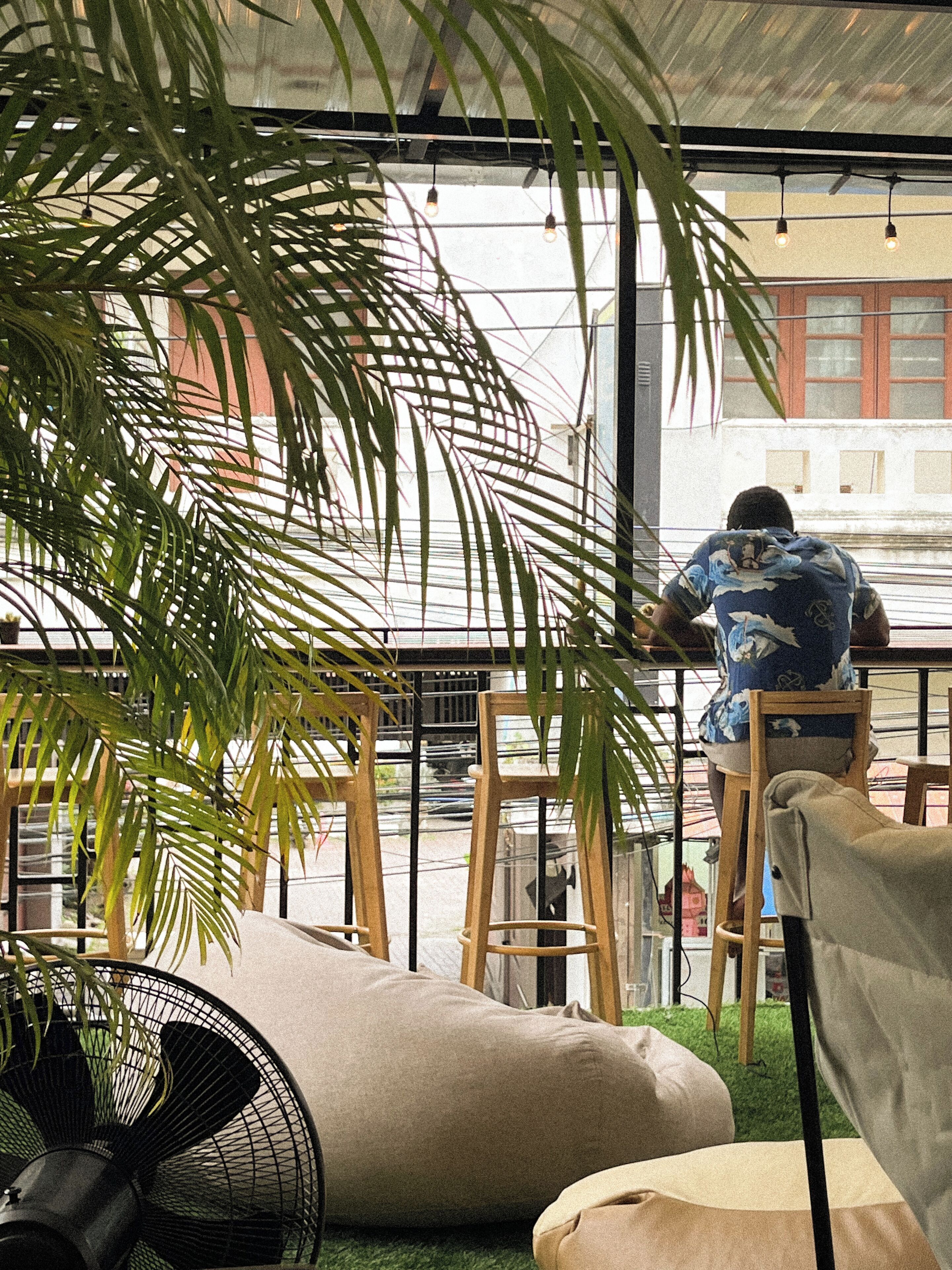 A room with a large window, a fan, and a person on a ladder.