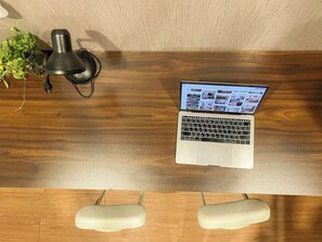 Una laptop sobre un escritorio de madera, con una planta y una lámpara.