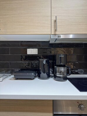 Een keuken met een modern ontwerp, met een zwarte koffiezetapparaat, een waterkoker en een broodrooster op het aanrecht.