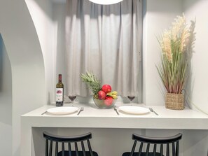 Een eettafel met een fles, glazen en een schaal fruit.