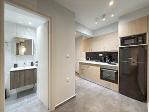 A modern kitchen with a built-in oven, microwave, and a black refrigerator. - SmartLiving Central Apt 1 (Thessaloniki)