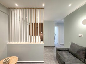 Een moderne woonkamer met een bank, een houten tafel en een scheidingswand met verticale lamellen.