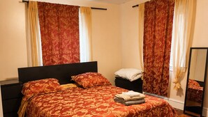 Ein Schlafzimmer mit einem großen Bett, einem Deckenventilator und Vorhängen.