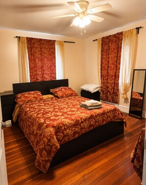 Ein Schlafzimmer mit einem großen Bett, einem Deckenventilator und Vorhängen.