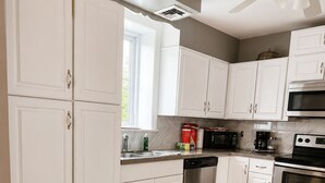 Eine moderne Küche mit weißen Schränken, einem Geschirrspüler, einer Mikrowelle und einem Backofen.