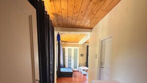A hallway with wooden flooring, a staircase, and a door leading to a room with a white wall and a cabinet. - Revivo The Confluenz (Manali)