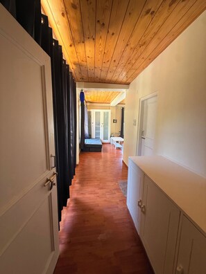 Un pasillo con suelo de madera, una escalera y una puerta que da a una habitación con pared blanca y un armario.