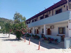 A two-story building with a covered porch, potted plants, and a clear sky. - kabile motel (Çanakkale/Ayvacık)