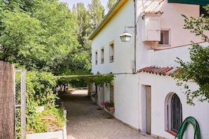 Un estrecho callejón adoquinado con un edificio blanco que tiene ventanas arqueadas y un toldo verde.