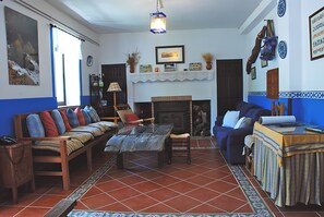 Una sala de estar con sofá, una mesa, chimenea y suelo con baldosas azules y blancas.