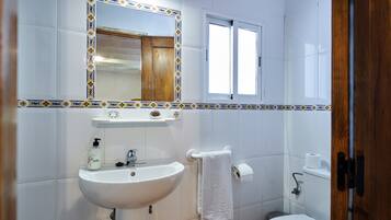 Une salle de bain équipée d’un lavabo, d’un miroir, de toilettes et d’une fenêtre.