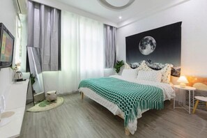 A bedroom with a bed, a side table, a lamp, a painting of the moon, and a window with curtains. - Compass B&B(Zhangjiajie Tianmenshan Ropeway Store) (Zhangjiajie)