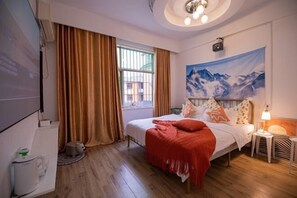 A bedroom with a bed, a window with curtains, a painting on the wall, and a lamp on a bedside table. - Compass B&B(Zhangjiajie Tianmenshan Ropeway Store) (Zhangjiajie)