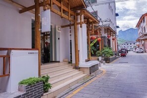 A building with a wooden porch, steps, and a sign. - Compass B&B(Zhangjiajie Tianmenshan Ropeway Store) (Zhangjiajie)