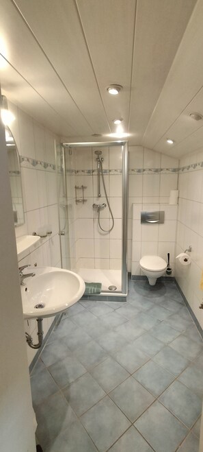 Un baño con ducha de vidrio, lavamanos, inodoro y bidé.
