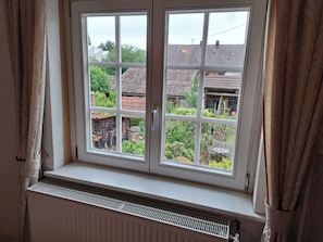 Une fenĂŞtre donnant sur un jardin et les maisons voisines.