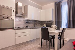 Eine moderne Küche mit weißen Schränken, Edelstahlgeräten und einem Essbereich mit Tisch und Stühlen.