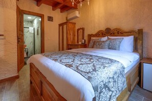 Une chambre à coucher avec un lit en bois, une table de chevet, un miroir et une armoire.