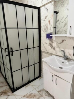 Uma casa de banho com uma pia branca, um espelho e chão em azulejos.