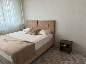 Een hotelkamer met een groot bed, een nachtkastje en een kamerbreed tapijt met dessin.