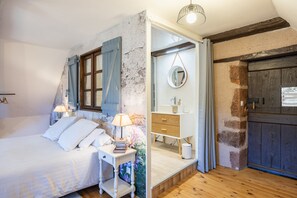 Un dormitorio con cama, mesita de noche, lámpara y espejo.