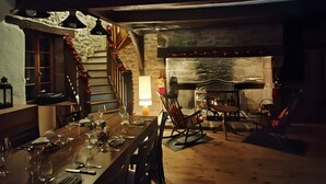 Un acogedor comedor con chimenea de piedra, escalera de madera y una mesa para cuatro.