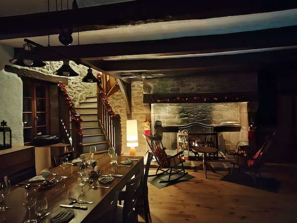 A cozy dining area with a stone fireplace, wooden staircase, and a dining table set for four.