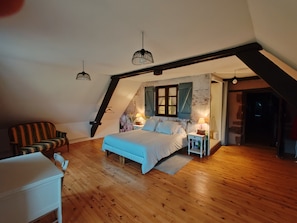 A bedroom with a sloped ceiling, a bed, a chair, bedside tables, and hanging lights. - Sans Chichi Chambres et Table: Mountain View, Shared Terrace & Wi-Fi (Escandolières)