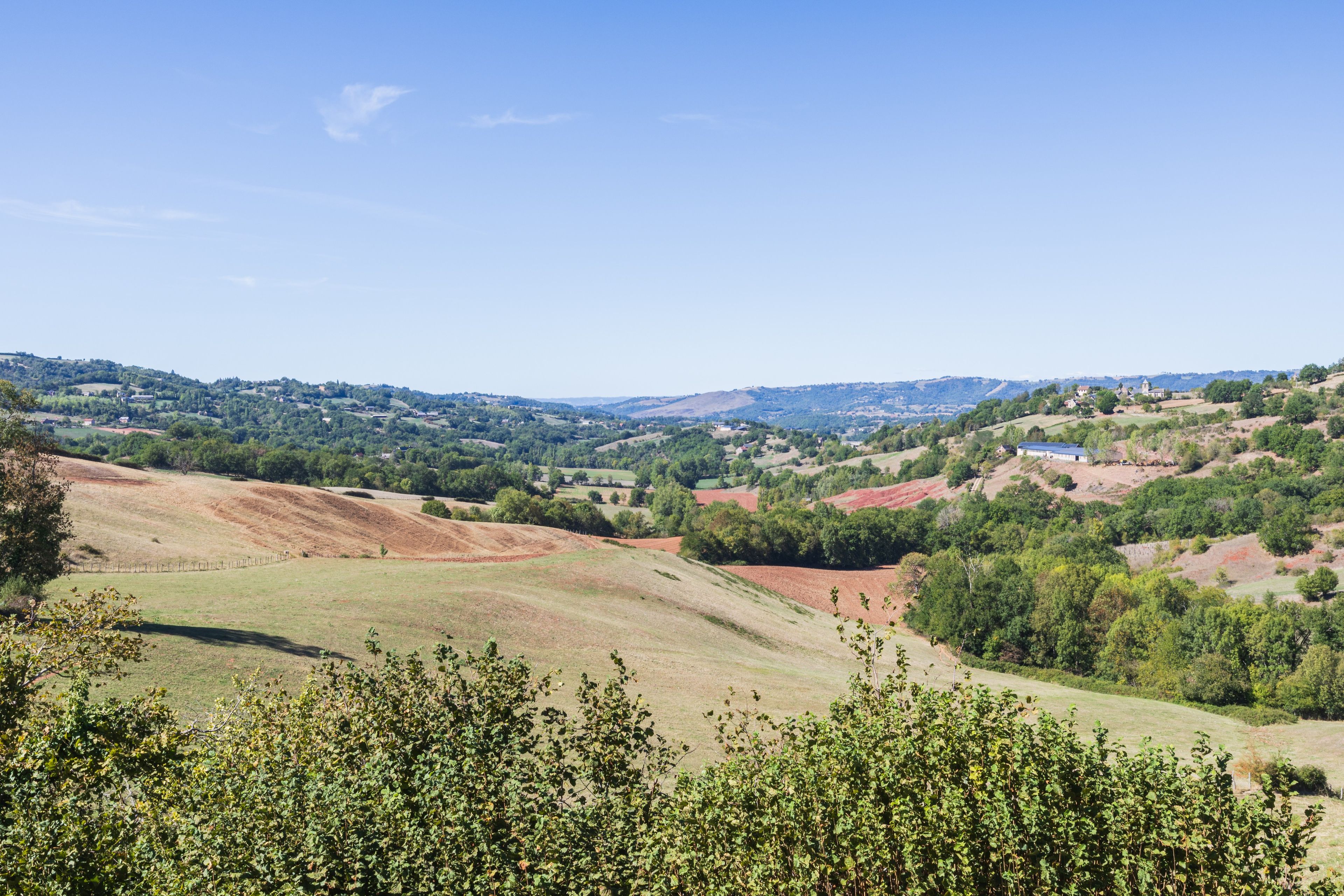 A panoramic view of a hilly landscape with scattered buildings and greenery.