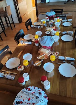 A dining table set with plates, bowls, cutlery, and various food items, indicating a meal setup. - Sans Chichi Chambres et Table: Mountain View, Shared Terrace & Wi-Fi (Escandolières)
