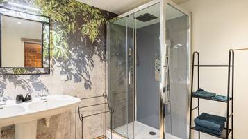 Une salle de bain avec une douche à parois de verre, un lavabo blanc et un porte-serviettes.