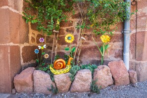 A garden wall with a snail sculpture, various flowers, and climbing plants.