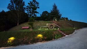 Ländliche Landschaft mit einem hölzernen Wagen, einer Bank und einer Treppe, die einen Hügel hinaufführt.