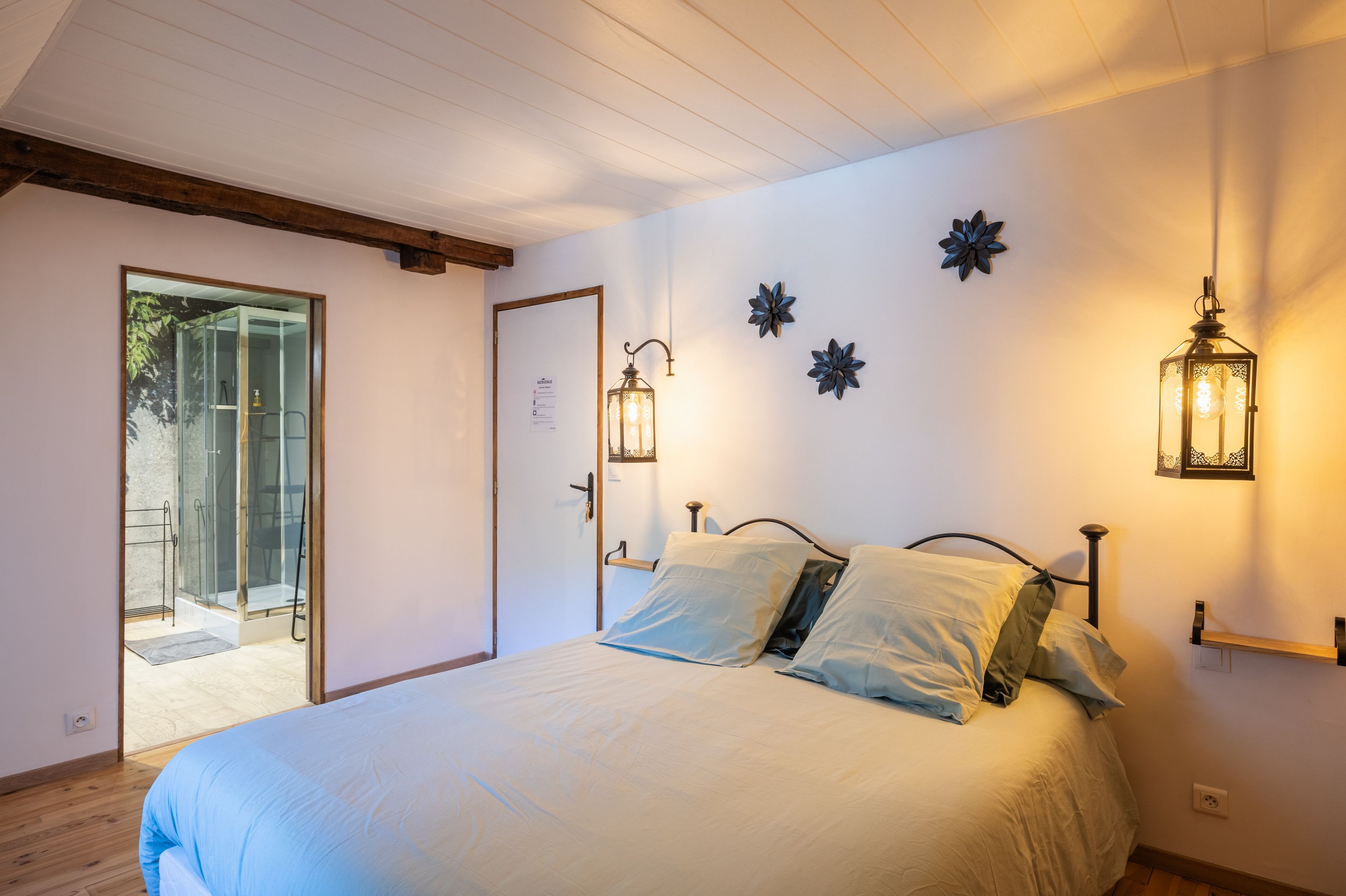 Une chambre à coucher avec un lit, une porte et un luminaire fixé au mur.