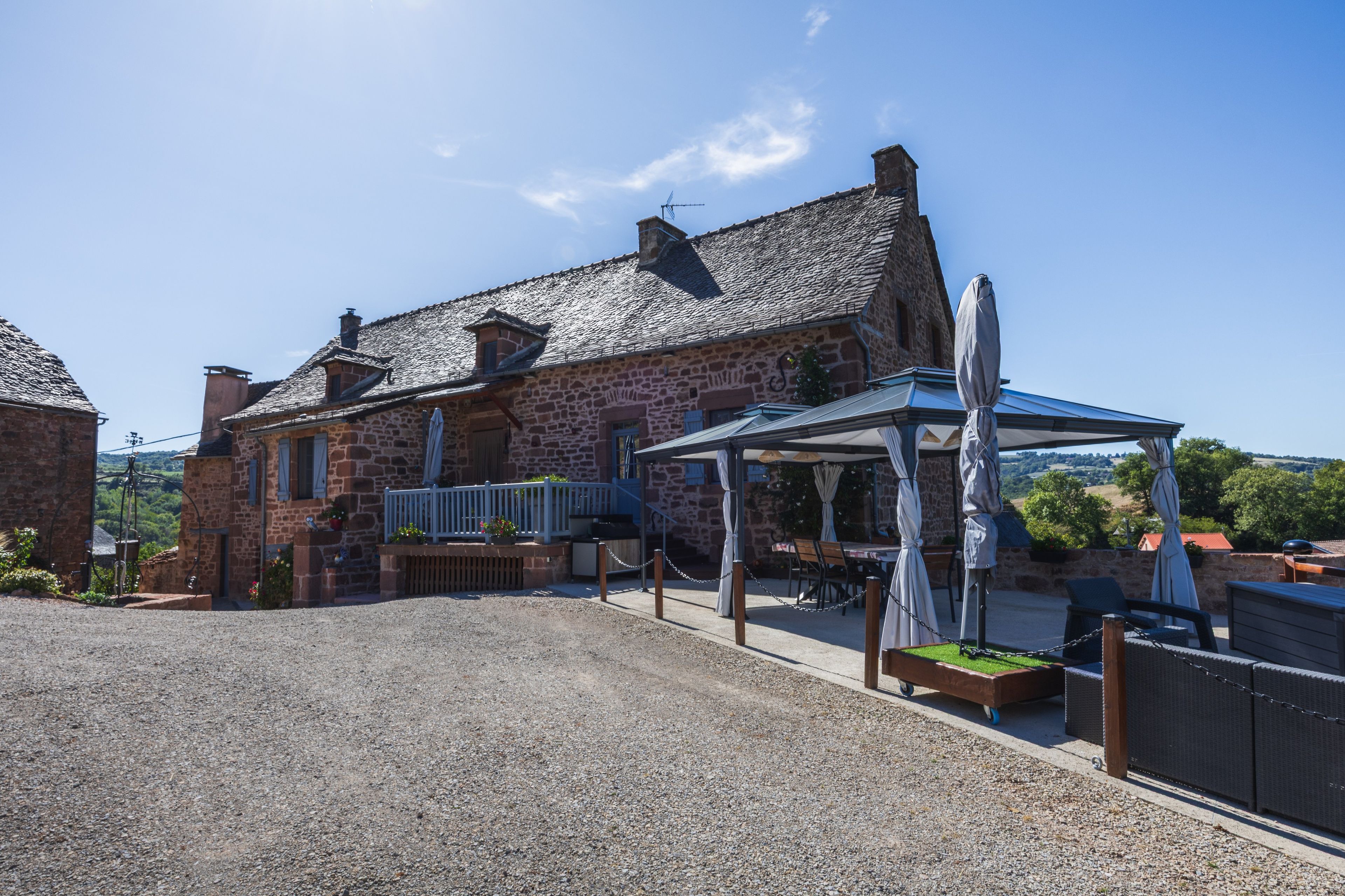 Un bâtiment en pierre doté d’un espace extérieur aménagé avec des sièges, protégé par un auvent.