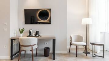 Une chambre moderne équipée d’un bureau, de deux chaises, d’une machine à café, d’une poubelle et d’un lampadaire.