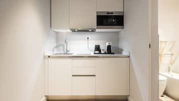 Una cocina compacta con horno integrado, cafetera y pileta.