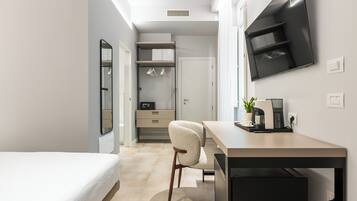 Habitación de hotel moderna con cama, escritorio, silla, televisor y armario.