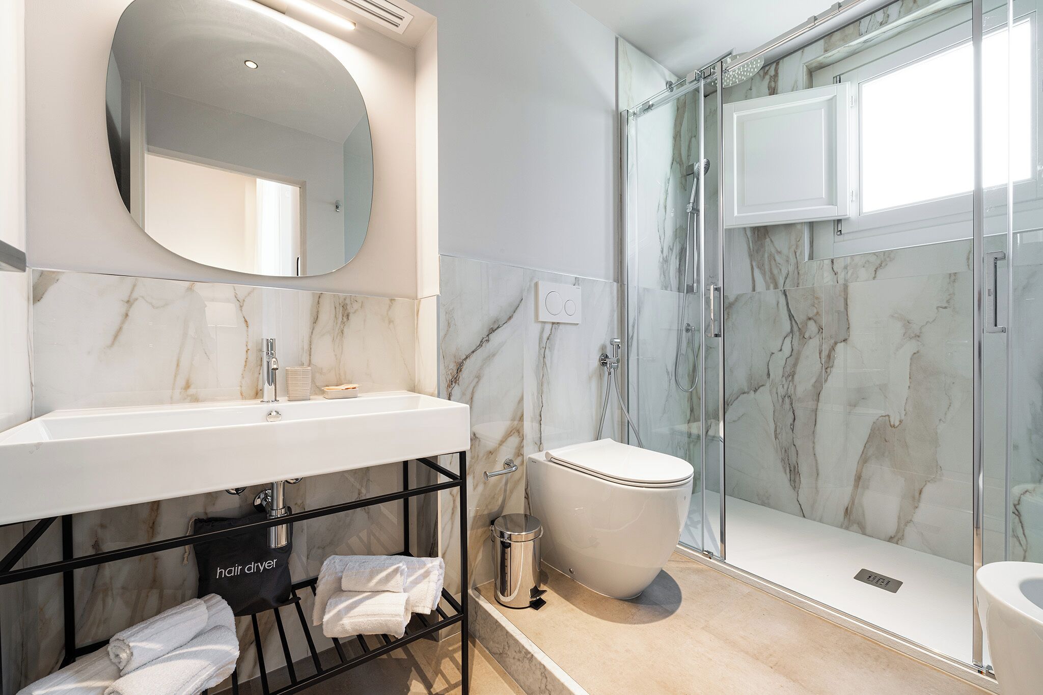 Une salle de bain moderne avec un lavabo en marbre, des toilettes et une douche à parois de verre.