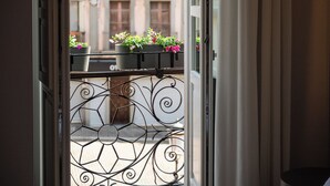 Vista a través de una puerta con barandilla de balcón metálica y macetas de flores.