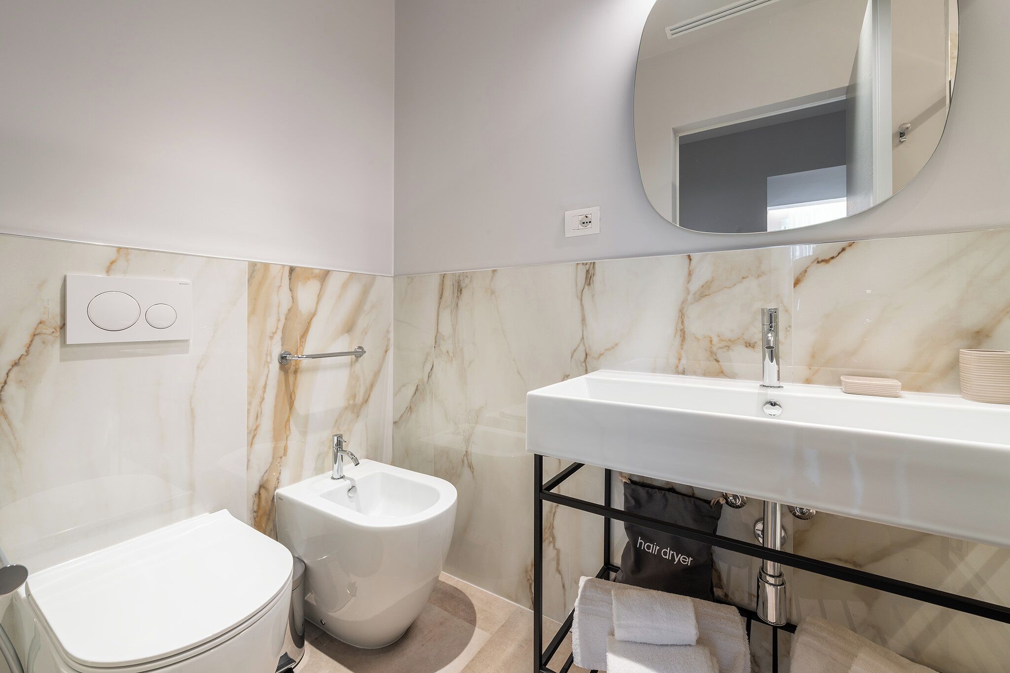 Un baño moderno con bidé, inodoro, lavabo y un perchero para toallas.