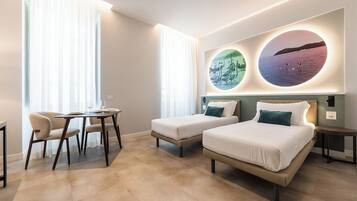 Ein Hotelzimmer mit zwei Betten, einem kleinen Tisch und Stühlen. An der Wand befinden sich zwei runde Leuchten mit Abbildungen.