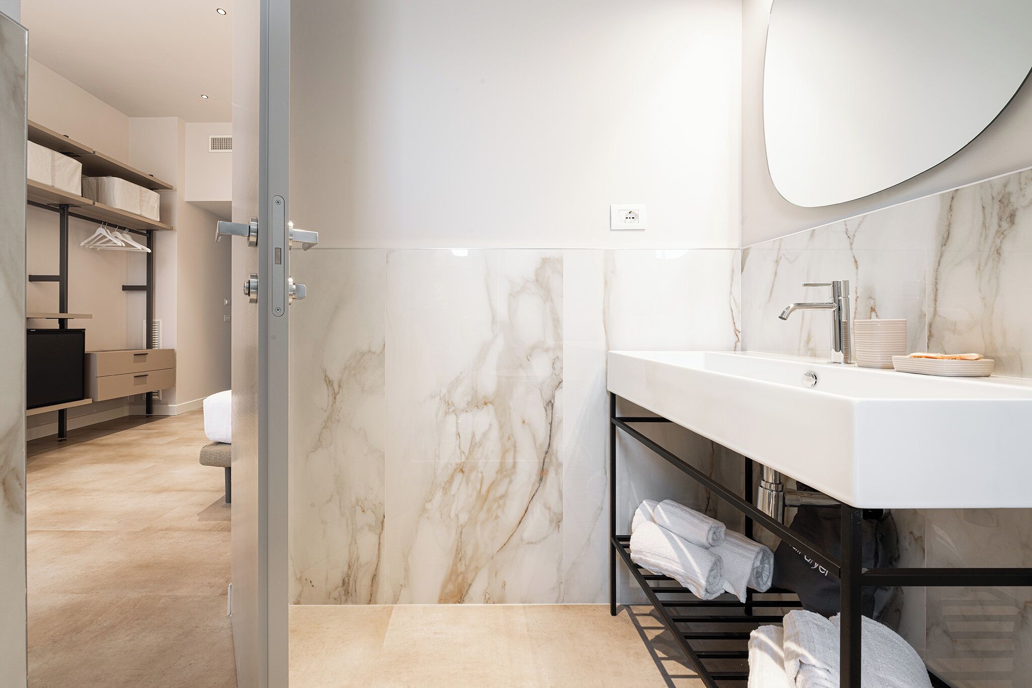 Une salle de bain moderne avec un mur en marbre, un lavabo et un porte-serviettes.