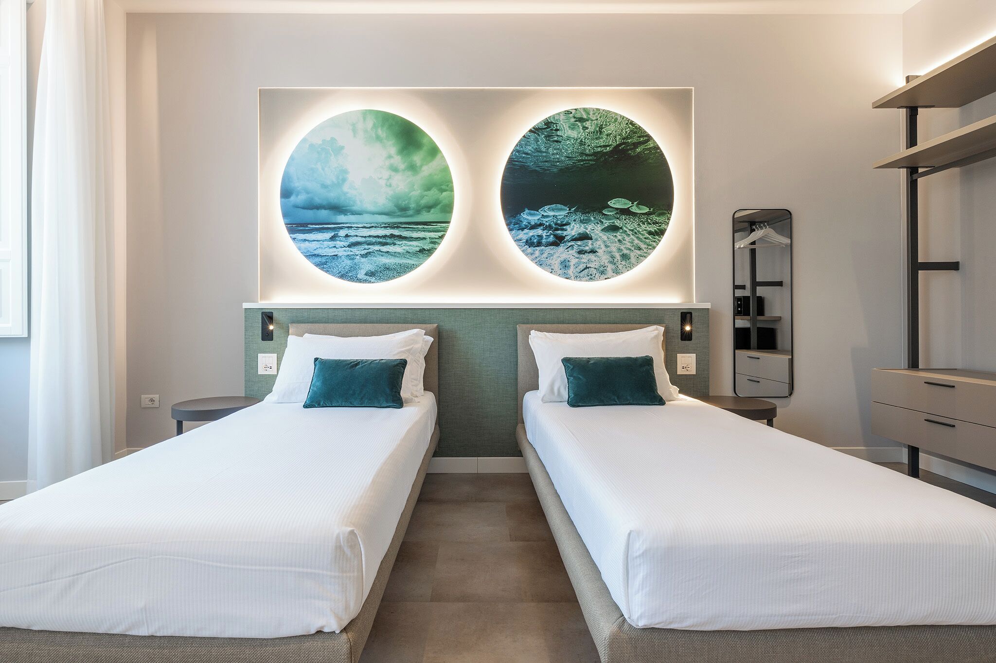 Een hotelkamer met twee bedden, een groot kunstwerk aan de muur, een spiegel en een kledingkast.